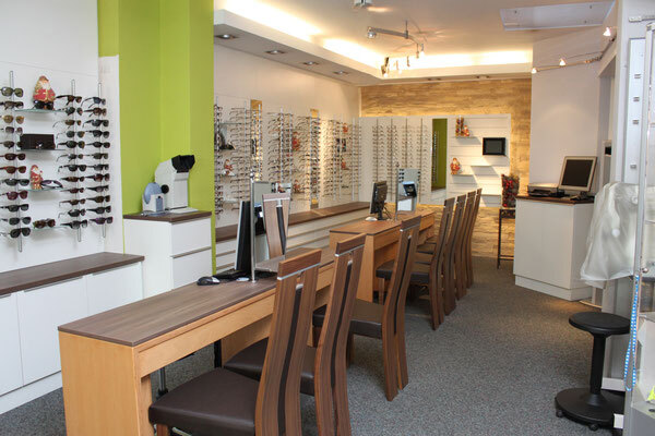 Modernes Optiker-Geschäft mit Brillenregalen, Beratungstischen und Computerarbeitsplätzen.
